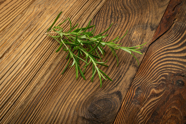 Friss rozmaringgallyak az asztalon. Zöld rozmaring ág, fűszerezés ágak, romarin gyógynövények, fűszer fű fa rusztikus háttér - Fotó, kép