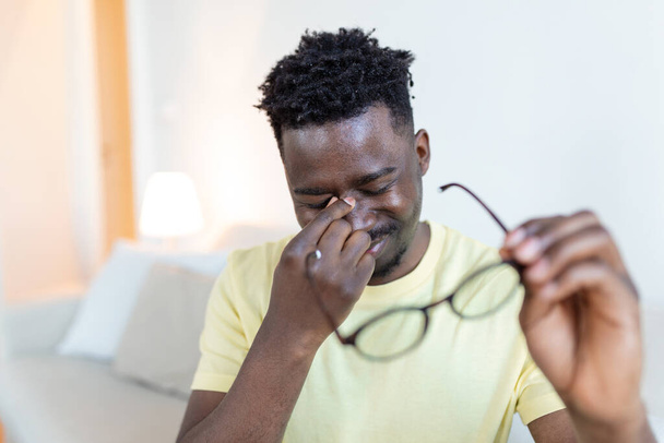 L'homme africain à lunettes se frotte les yeux, souffrant d'yeux fatigués, concept de maladies oculaires - Photo, image