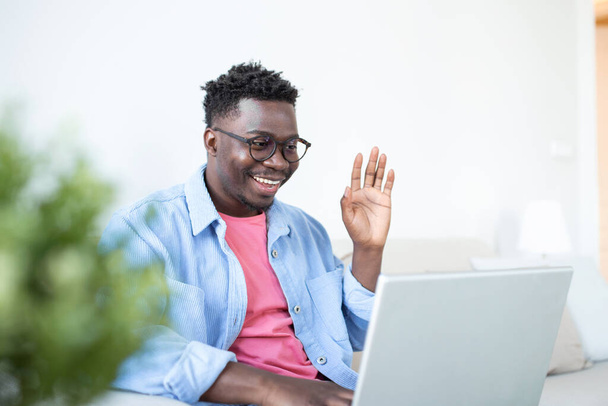 Jonge en vastberaden zwarte student studeert 's nachts thuis, met behulp van een laptop computer, en heeft een internetgesprek. - Foto, afbeelding