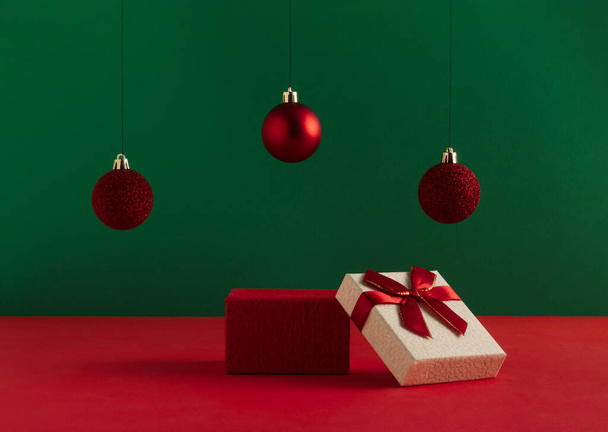 Creative Christmas concept made of podium and red baubles on bold green background. Minimal New Year advertisement concept. Mock up showcase for product, promotion, sale or presentation. - Фото, зображення