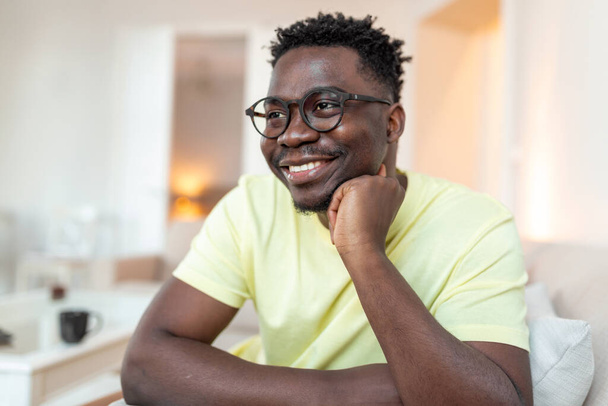Photo de profil du jeune afro-américain souriant en lunettes pose dans son propre appartement à la maison. Gros plan portrait tête d'homme biracial heureux millénariste locataire ou locataire dans les lunettes montrent optimisme. - Photo, image