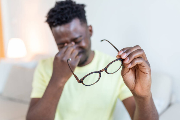L'homme africain à lunettes se frotte les yeux, souffrant d'yeux fatigués, concept de maladies oculaires - Photo, image