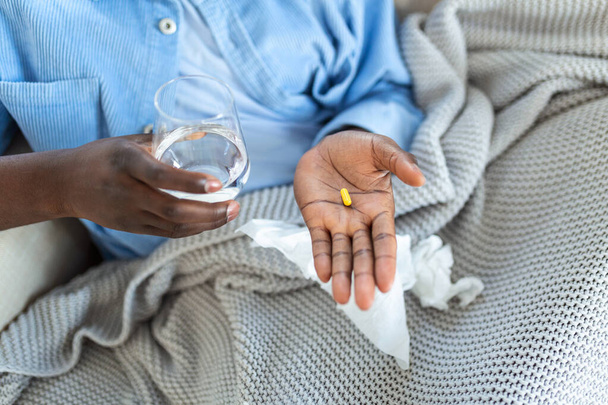 Schwarzer hält Tabletten und Gläser in den Händen. Konzept der Gesundheitsfürsorge und Medizin: Patienten nehmen täglich verschriebene Medikamente ein, fühlen sich krank, Antibiotika, Schmerzmittel oder Antidepressiva. Nahaufnahme - Foto, Bild