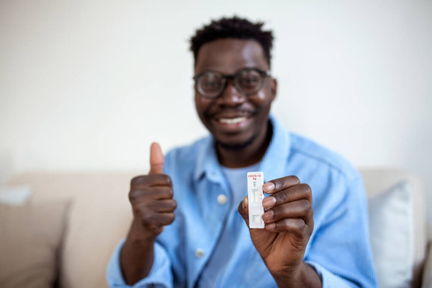 African-American man holding a negative test device. Happy young man showing his negative Coronavirus - Covid-19 rapid test. Coronavirus - Photo, Image