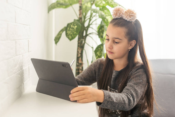 Chica adolescente feliz en línea con un ordenador portátil en la sala de estar en casa. - Foto, imagen