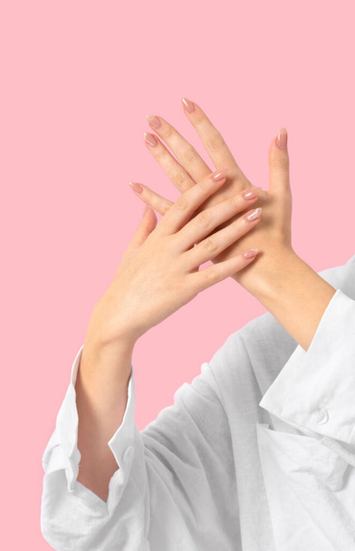 Руки красивые ухоженные с женским бежевым мрамором дизайн ногтей гель лак на розовом фоне. Концепция салона красоты маникюр, педикюр. - Фото, изображение