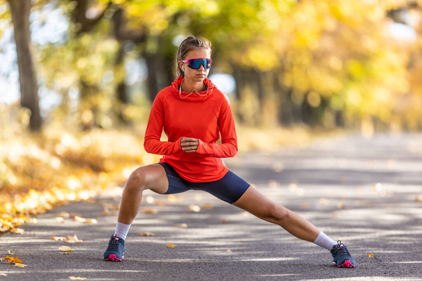 Young female athlete in sportswear is warming up before running  - Фото, зображення
