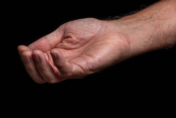 Крупним планом, зморщена права рука літнього чоловіка просить допомоги на чорному тлі
.  - Фото, зображення