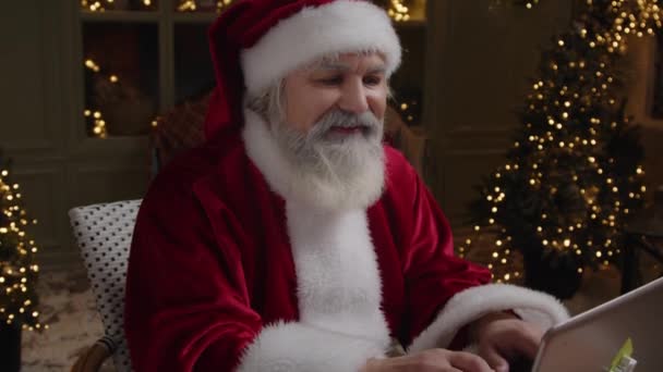 Happy Santa Claus pracuje ve své rezidenci, připravuje se na dovolenou, psaní dopisu na notebooku, Close up, Zpomalený pohyb. - Záběry, video