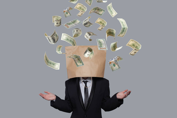 Liiketoiminnan harjoittaja, jolla on paperipussi päässä rahan alla, sade eristetty harmaalla pohjalla - Valokuva, kuva