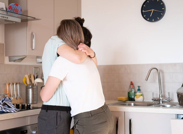 Evdeki mutfakta sarılan lezbiyen bir çift. - Fotoğraf, Görsel