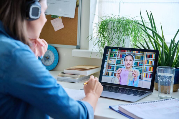 Young female teacher in headphones having video conference call with teenage girl student using laptop home. Online lesson e-learning distance remote classes technology in education knowledge school - Photo, Image