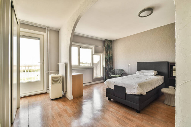 Комфортне ліжко і паркетна підлога в просторій спальні з інтер'єром в мінімальному стилі
 - Фото, зображення