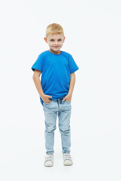 Stylish child boy model in a blue casual t-shirt on a white isolated background - Фото, изображение