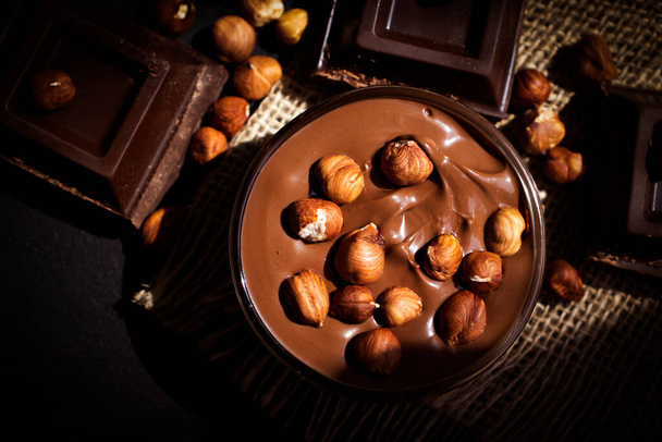 Chocolate spread with hazelnuts on a dark background - Photo, Image