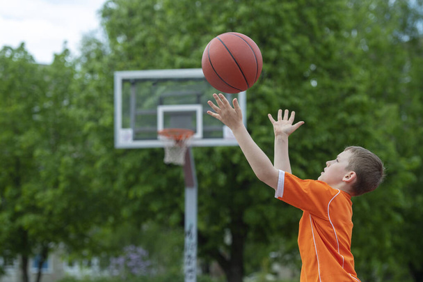 Chlapec hraje basketbal na hřišti. Koncept sportovního životního stylu, trénink, tábor, volný čas, dovolená. Horizontální sportovní motiv plakát, pohlednice, záhlaví, webové stránky a aplikace - Fotografie, Obrázek