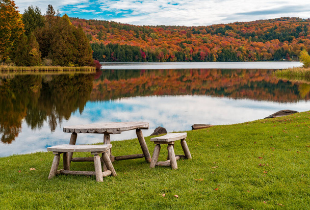 Rustic wooden table and chairs by Silver Lake in Barnard Vermont during the fall season - Photo, Image