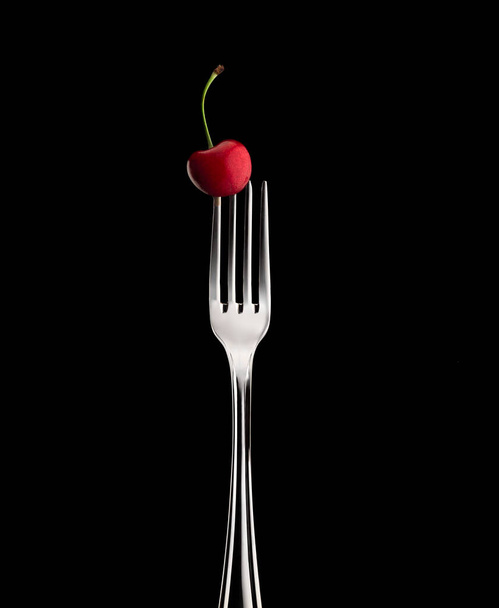fork with cherry on black background - Φωτογραφία, εικόνα