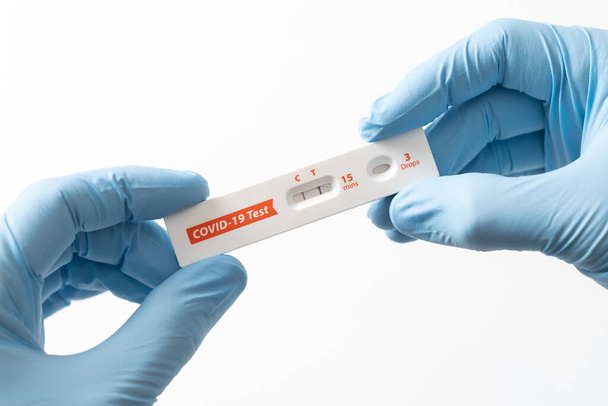 Hand is showing positive results on test strip for rapid antigen home Covid-19 test kit at home. - Fotoğraf, Görsel