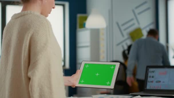 Woman holding tablet with green screen mockup display standing in busy startup business at desk. Office worker looking at digital device with chroma key touchscreen comparing charts with laptop. - Záběry, video