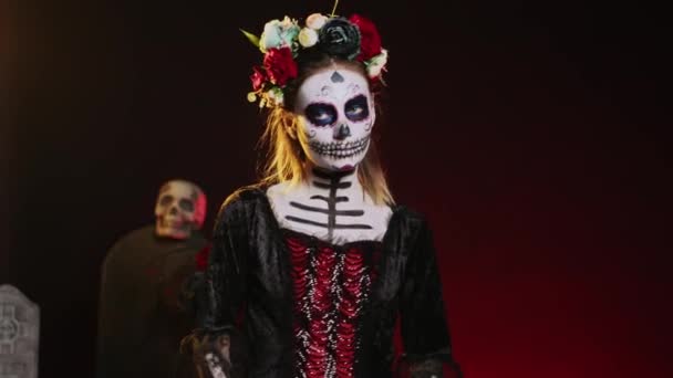 Santa diosa de la muerte posando en traje de halloween con cráneo maquillan para celebrar dios de los muertos en fiesta mexicana. Mujer espeluznante como santa muerte con arte corporal en blanco y negro. Disparo de mano. - Metraje, vídeo