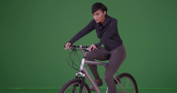 Jeune femme afro-américaine en tenue de sport conduisant son vélo vers la caméra gauche sur écran vert. Sur écran vert à saisir ou à composer. - Séquence, vidéo