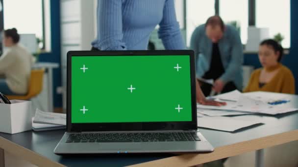 Laptop computer with green screen on desk in front of african american startup employee looking at paper with charts. Focus on portable computer screen with chroma key empty background. - Záběry, video