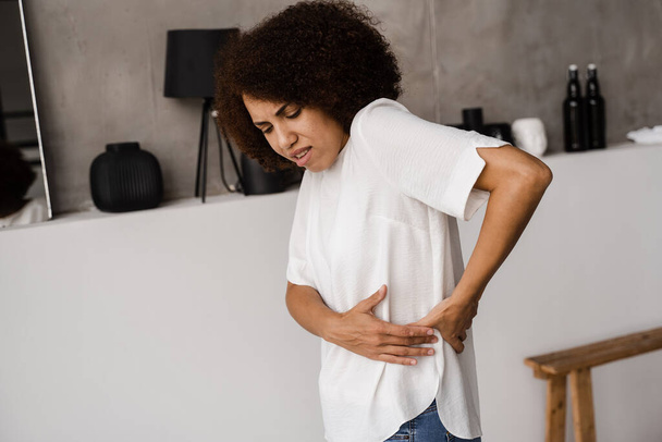 Infezione renale pielonefrite infezione del tratto urinario. Donna afroamericana sente mal di schiena dolore alla colonna vertebrale a causa della malattia di pielonefrite UTI - Foto, immagini