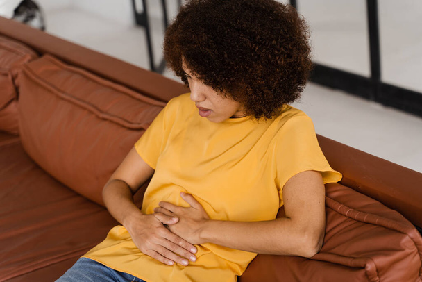 Magenschmerzen. Kranke Afroamerikanerin hält Bauch, weil es weh tut. Pankreatitis der Bauchspeicheldrüse entzündet sich - Foto, Bild