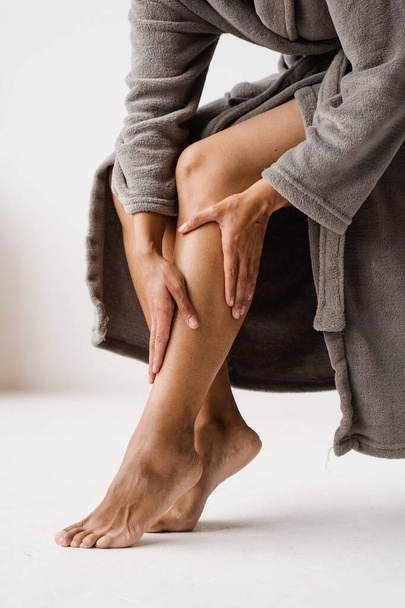 Африканська американка торкається ніг і дивиться на вени. Глибокий тромбоз вени варикоза женщины. Процедура склеротерапії під час відвідування судинного хірурга - Фото, зображення