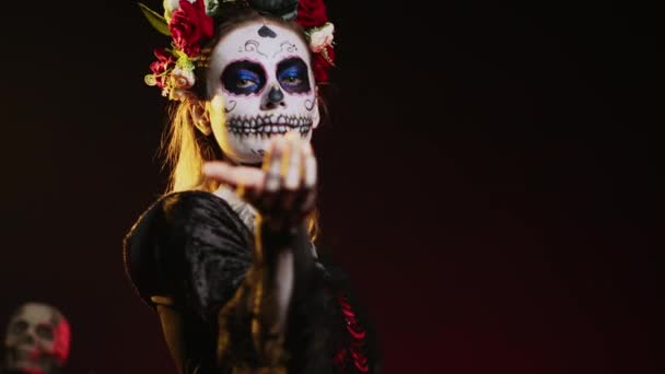 Flirty goddess of dead calling and luring victims, looking like la cavalera catrina with skull black and white make up. Holy santa muerte costume on mexican holiday horror celebration. Handheld shot. - Footage, Video