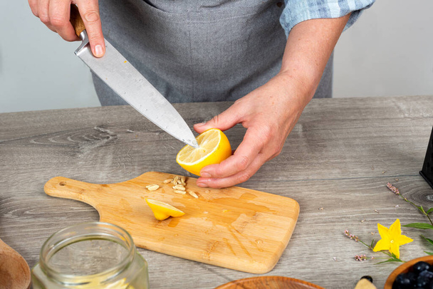 woman's hand cuts and peels a lemon. - Foto, Imagem