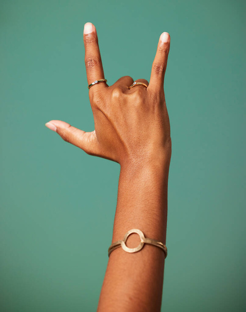 Peace love and rock n roll. a hand making a gesture shot against a studio background - Foto, imagen