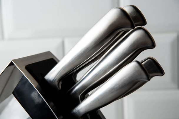 um conjunto de 5 facas de cozinha em um suporte fica sobre a mesa, close-up - Foto, Imagem