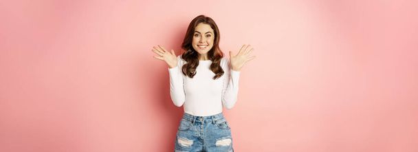 Happy attractive woman brunette smiling, looking with disbelief and excitement, winning, celebrating, reaction to great good news, pink background. - Fotografie, Obrázek