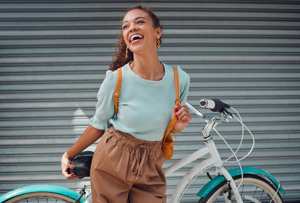 Bicycle, travel and black woman student excited for outdoor lifestyle, eco friendly cycling transport on garage door background. Gen z girl with bike and backpack on her way to college or university. - Photo, Image