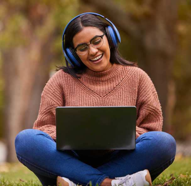 Laptop, zene és lány tanul a parkban, beszél egy video hívás vagy tanulás az interneten Svédországban. Boldog, mosolygós és pihenni tanuló olvasás a pc oktatás és a tudás podcast a természetben. - Fotó, kép