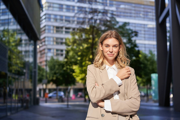 Femme d'entreprise élégante, jeune femme patron en costume, l'air confiant et heureux, posant à l'extérieur dans la rue. Femme d'affaires - Photo, image