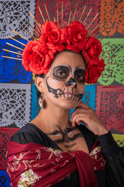 Egy mexikói nő portréja hagyományos sminkben és Catrina jelmezben. Színes vágott papír háttér - Fotó, kép