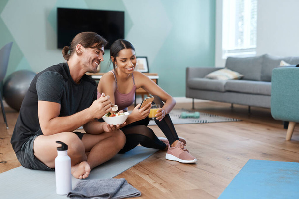 A good diet goes hand in hand with every workout. Full length shot of an athletic young couple enjoying some healthy snacks after their workout at home - Fotoğraf, Görsel