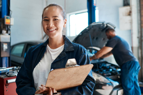 I bring smiles to peoples faces by fixing their car problems. a female mechanic holding a clipboard while working in an auto repair shop - Valokuva, kuva