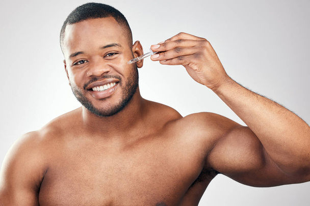 I dont mind adding extra steps to my skincare routine. Studio portrait of a handsome young man applying serum to his face with a dropper against a white background - Foto, immagini