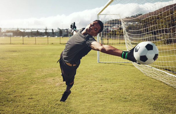 Soccer, sports and goalkeeper training on a field for a professional competition. Young and strong athlete with energy and motivation catching a football during a game or exercise on a sport ground. - Foto, Imagem