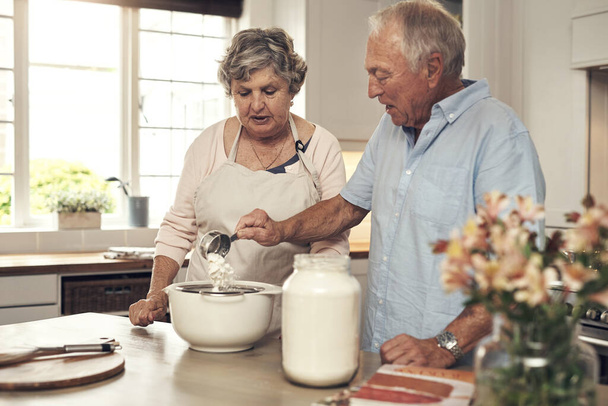Dont forget to add in a little love. a senior couple baking together at home - Fotoğraf, Görsel