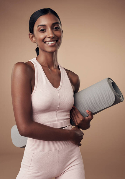 Its a workout day dedicated to my core. an attractive young woman standing alone in the studio and holding a yoga mat - Photo, Image