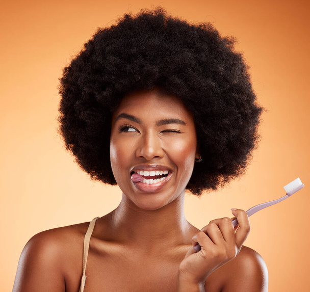 黒の女性は、歯のホワイトニング、オレンジの背景に保護と口腔衛生のための歯の健康のための歯ブラシ。口の掃除と美しさのためにポーズ漫画の女性のアフロ、健康と笑顔. - 写真・画像