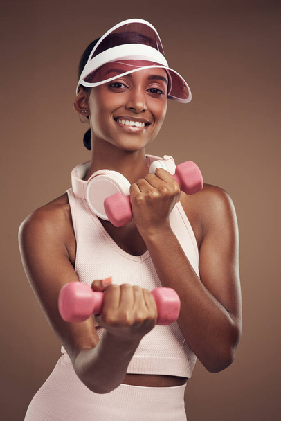 Leaner arms, here I come. an attractive young woman standing alone in the studio and using dumbbells while working out - Fotó, kép