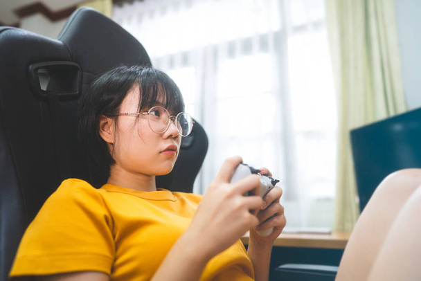 Nerd-Stil junge erwachsene asiatische Gamer Frau mit Brille spielen ein Online-Spiel. Wettstreit um die Siegerlaune. Menschen Freizeit Lebensstil zu Hause. - Foto, Bild