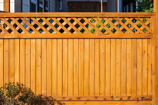 Ωραίος ξύλινος φράχτης γύρω από το σπίτι. Ξύλινο φράκτη με πράσινο γκαζόν. Φωτογραφία δρόμου, κανείς, επιλεκτική εστίαση - Φωτογραφία, εικόνα