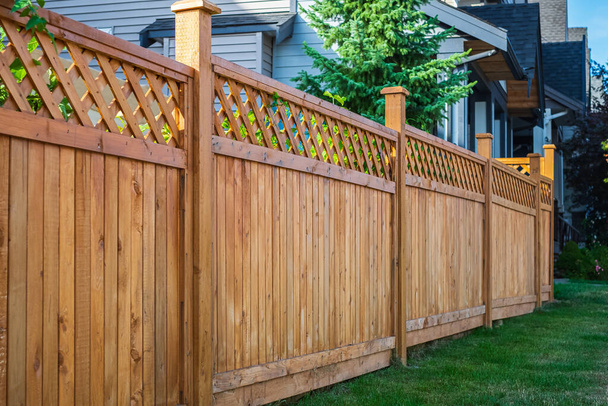 Nice new wooden fence around house. Wooden fence with green lawn. Street photo, nobody, selective focus - Photo, Image